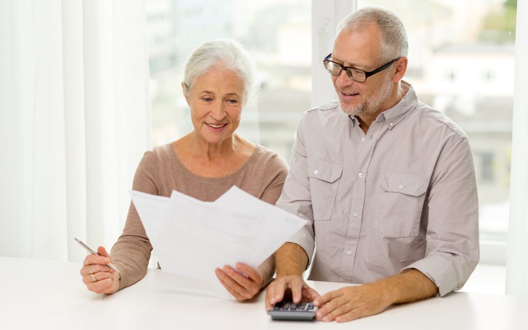 smiling homeowner couple in front of bills with calculator in hand